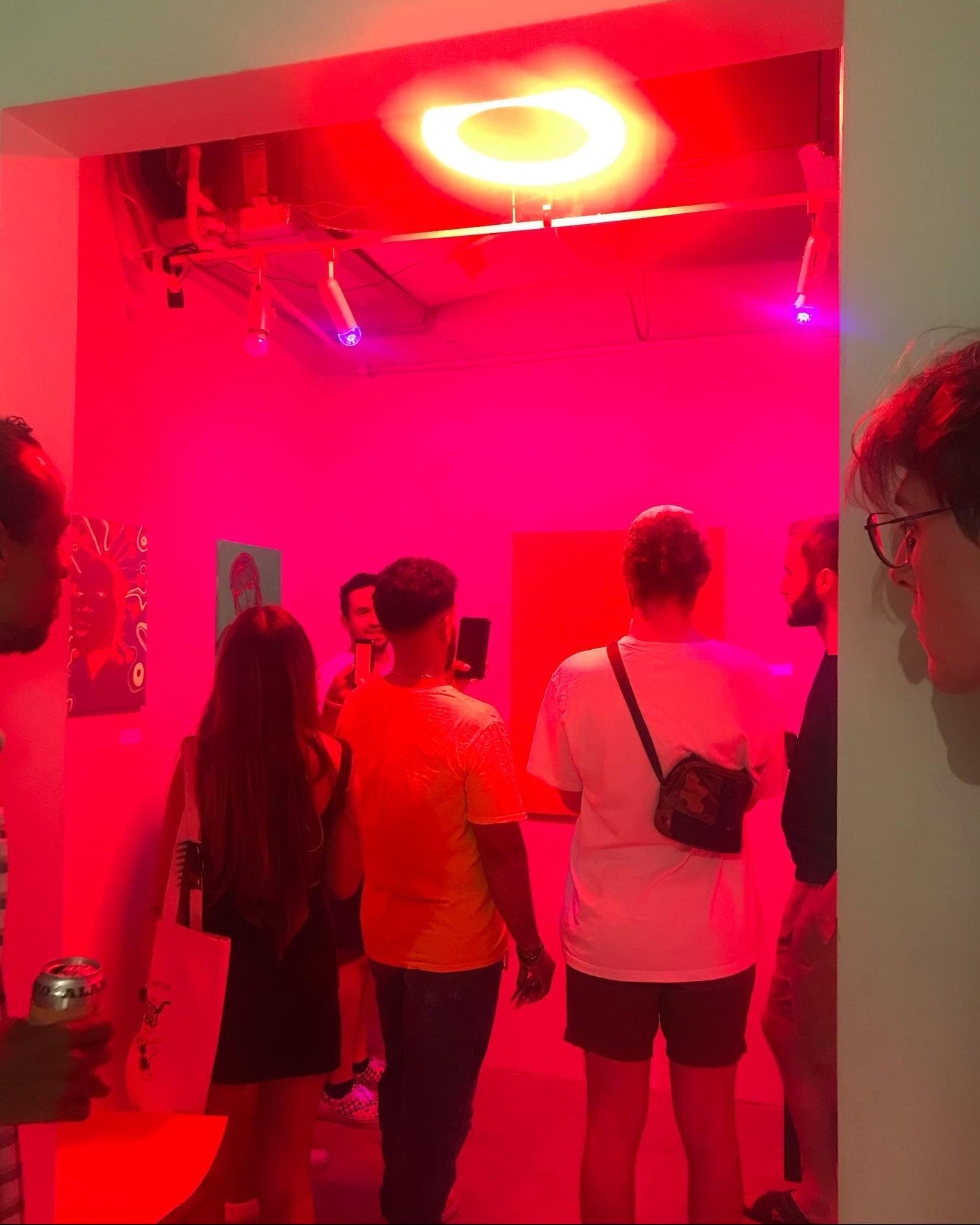 People in a room with red lighting and a glowing light fixture.